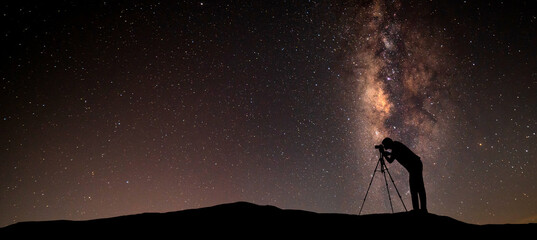 Milky Way.Warm Color night sky with stars and silhouette of a standing Cameraman on the stone.milky...