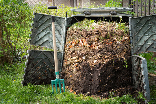 Layers of rotting compost in plastic composter bin in garden