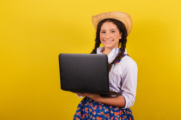 Girl wearing typical clothes for Festa Junina. Holding Notebook, Laptop, Technology. For the Arraia...