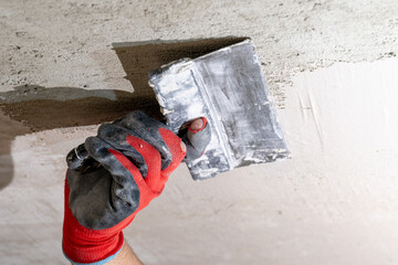 The master in gloves aligns the ceiling with lime plaster close up.