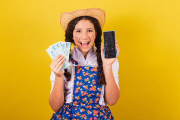 Girl wearing typical clothes for Festa Junina. holding cellphone and money bills, apps, technology....