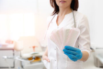 Portrait gynecologist hold absorbent panty liners for woman in modern clinic, sunlight background