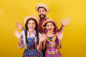 Father and daughters wearing typical clothes for the Festa Junina. surprised, wow, incredible,...