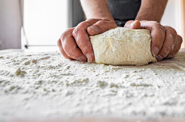 Man Hands kneading dough for pizza on the wooden table