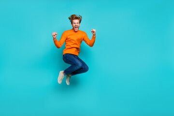 Full length photo of lucky impressed guy dressed orange sweater jumping high empty space isolated...