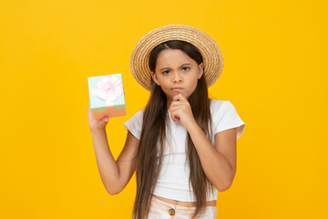pondering teen child hold present box on yellow background - obrazy, fototapety, plakaty
