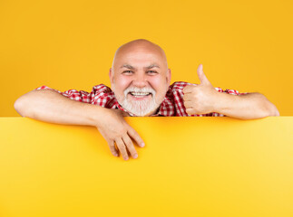 cheerful senior man with copy space on blank banner. advertising. thumb up