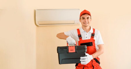 Man professional technician in red overall fixing the AC air conditioner