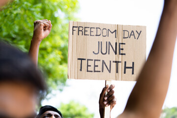 concept of Juneteenth freedom day march showing by close up protesting hands sign board - concept...