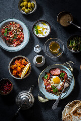 Turkish breakfast table. Flat-lay pastries, vegetables, greens, olives, cheeses, fried eggs, spices, jams, honey, tea in copper pot and tulip glasses