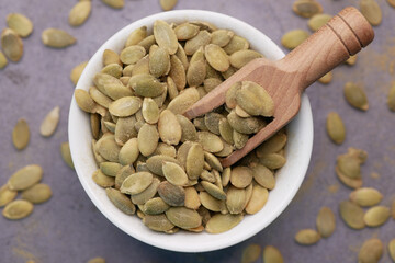  pumpkin seeds in a small bowl on black background 