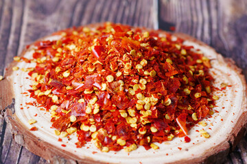 dried peppers flakes on a wooden plate on table 