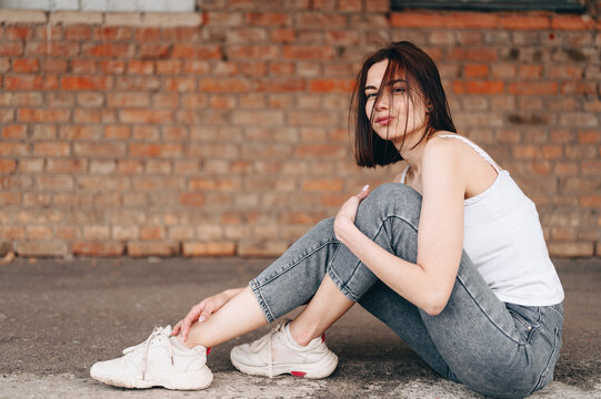 Side Shot Of A Beautiful Woman With A Sly Expression Sitting In The Center Of The Frame