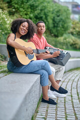 Girl with guitar and guy looking at camera