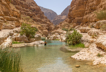 Tiwi, Oman - famous of its vertical cliffs and the green water, Wadi Shab is one of the most beautiful wadi in Oman, and a very popular tourist destination  - obrazy, fototapety, plakaty