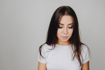 A young girl with makeup against a white wall looks down in close-up, free space under the text.