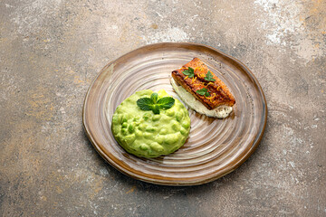 Pan seared white fish fillet with edamame puree on rustic background