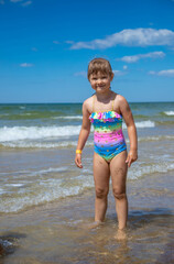 Happy child girl on the beach in warm summer day 