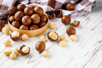 fresh macadamia nuts on a white wooden rustic background