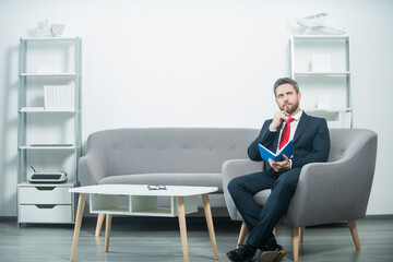 mature man in suit sit in office with planner