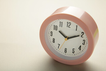 Pink clock on grey background. Top view.