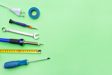 Repair tools on a green background. Measuring tape, screwdriver, soldering iron. Place for text. Copy space. Flat lay. Top view. Handyman tool kit. DIY. Advertising for the store.