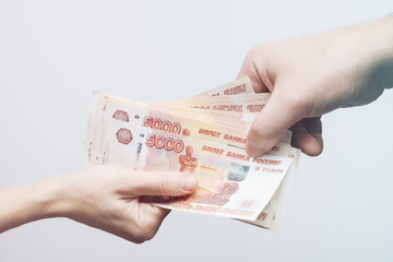 A woman's and a man's hand holds a pack of banknotes with a face value of five thousand rubles. Soft focus. Finance concept