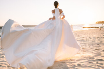 Happy young bride woman in white dress running, have fun on clean sandy beach waves of azure sea or...