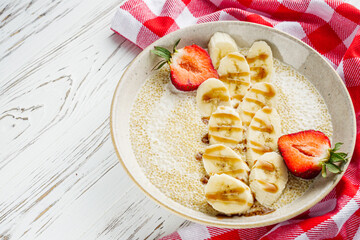 sweet porridge with quinoa and banana on a white rustic wooden background