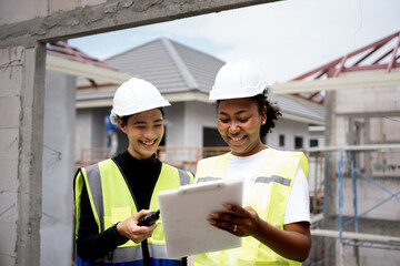 Team of beautiful female engineers inspecting the quality of house construction. Multi-ethnic group of Africans and non-Americans.female holding clipboard.ppe wearing safety firse concept.