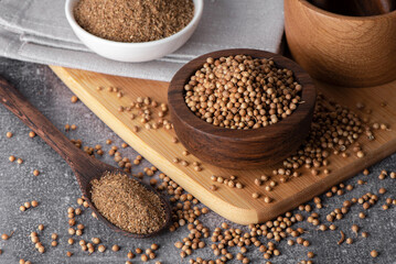 Coriander grains and coriander powder in a wooden bowl.
Coriander seeds. Coriander spice.