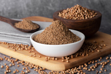 Coriander grains and coriander powder in a wooden bowl.
Coriander seeds. Coriander spice.