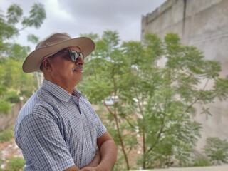 Picture of a person wearing sunglasses and hat out in a sanctuary in summers with green leaves in background