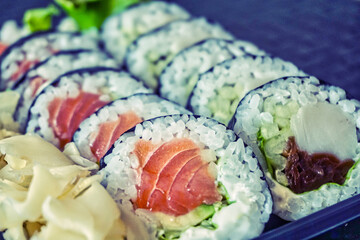 Sliced rolls of salmon and raw tuna sushi in plastic container