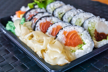 Sliced rolls of salmon and raw tuna sushi in plastic container