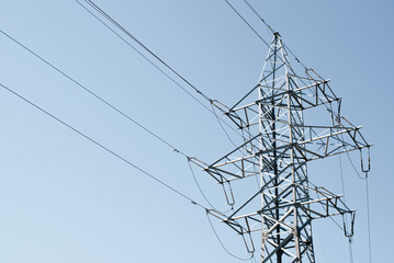 Iron tower and high voltage power line against the blue clear sky outdoors, copy space