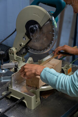 close-up of a woman carpenter cutting a block of wood with a chop saw