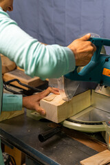 close-up of a woman carpenter cutting a block of wood with a chop saw