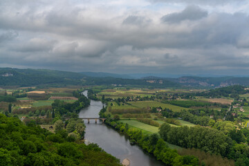view of the picturesque Dordogne Valley with river and bridge in dense green summer forest