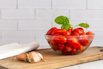 Tomates cherry orgánicos acompañados de ajo, aceite de oliva, sobre una mesada de mármol con luz de día. Concepto de alimentación saludable.