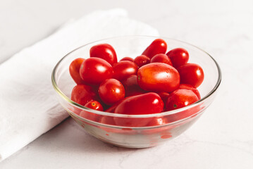 Tomates cherry orgánicos para ensalada, sobre mesada de mármol con luz de día. Concepto de alimentación saludable.