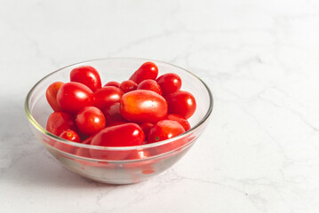 Tomates cherry orgánicos para ensalada, sobre mesada de mármol con luz de día. Concepto de alimentación saludable.