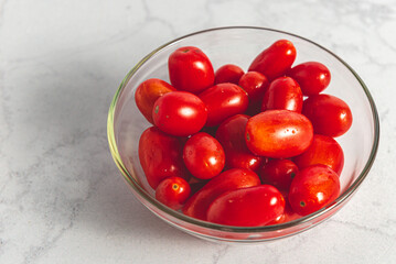 Tomates cherry orgánicos para ensalada, sobre mesada de mármol con luz de día. Concepto de alimentación saludable.