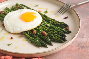 grilled asparagus, with fried egg, spices and herbs, parmesan cheese, on a beige plate, top view, rustic, no people