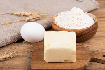 A bowl of flour, butter, an egg and dry spikelets on a coarse burlap cloth.