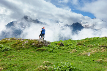 zwei Wanderer blicken in eine wolkenverhangene Bergwelt
