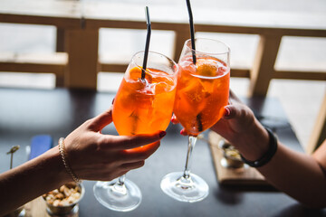 Aperol. Two glasses of aperol. People are holding glasses of aperol.