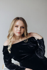 a pregnant woman blonde in a black dress lies in the studio on a white background holds her hand on her stomach
