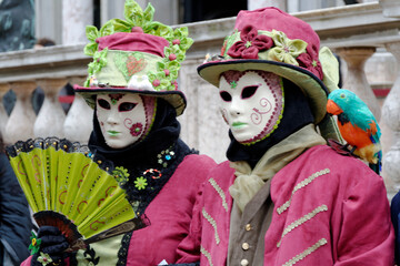 Obraz premium Venise, Italie, 27 février 2014 : Deux personnes déguisées, en vert et rose, masques, chapeau et éventail lors du carnaval de Venise