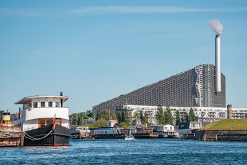 Amager Bakke, Slope or Copenhill, incineration plant, heat and power waste-to-energy plant and recreational facility in the district of Amager, Copenhagen, Denmark, with modern buildings and boats - obrazy, fototapety, plakaty